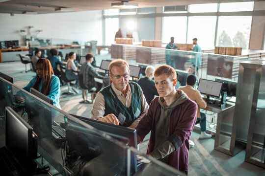 Teacher mentoring student at computer in modern university lab