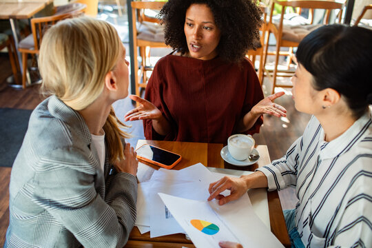 Three businesswomen in strategy meeting at coffee shop