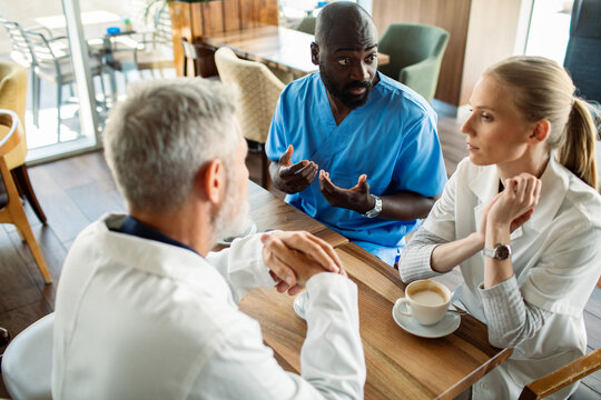 Doctors and nurse discussing patient case in hospital cafeteria