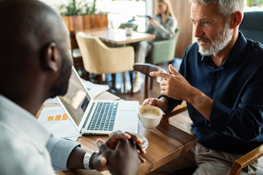 Two colleagues discussing data on laptop at cafe