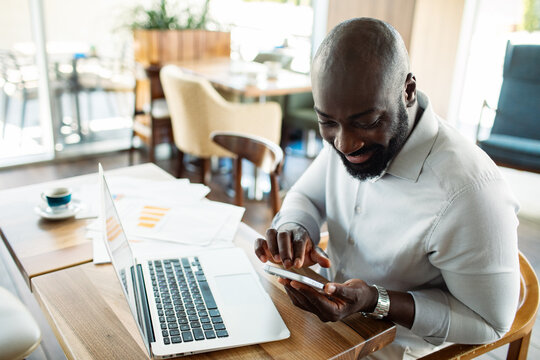 Businessman using smartphone and laptop in cafe