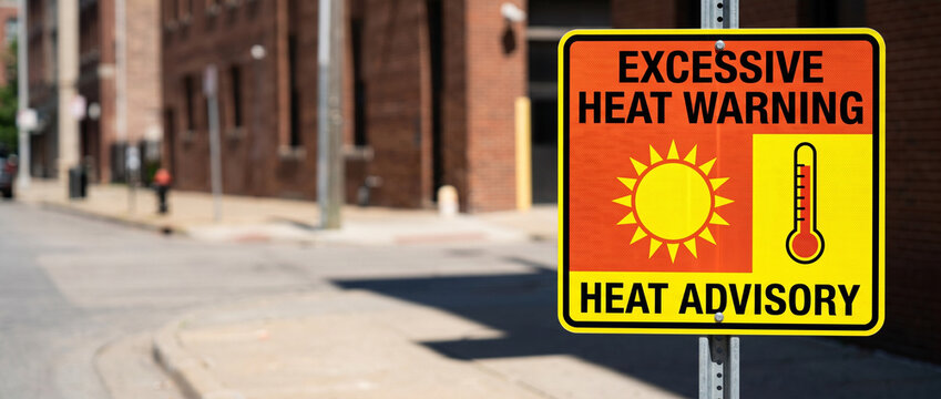 Excessive heat warning sign on city street. Danger of heatwave and extreme weather condition. Warning about intense summer temperature and public health risk in urban environment.