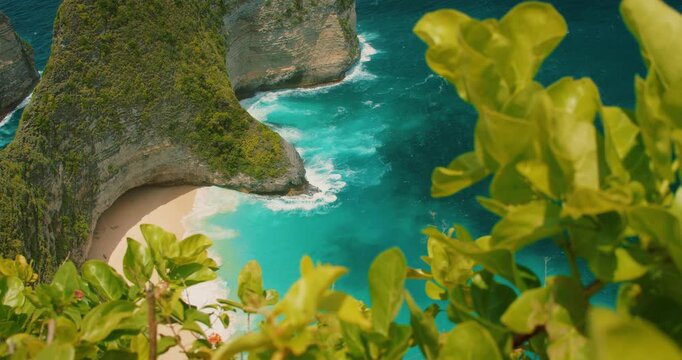 Coastal view of ocean waves crashing against limestone cliff base at Kelingking Beach Nusa Penida Bali