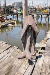 Obraz premium Pair of waders hanging on a pole on a wooden fishing dock
