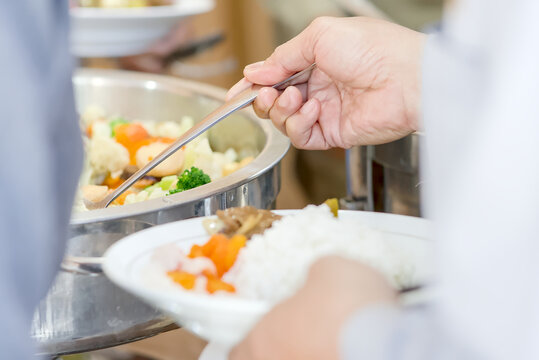 Close-up view of a festive dining moment showing a hand reaching for delicious food served on the table. The image captures the atmosphere of celebration, sharing, and culinary enjoyment, 