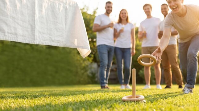 Group of young adult friends playing ring toss game on backyard lawn during summer garden party, leisure activity and outdoor recreation concept