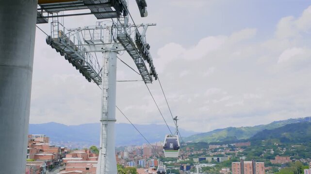 Medell&iacute;n, Antioquia, Colombia &ndash; Metrocable cable car operating above the city during daytime with mountain landscape and urban skyline, recorded at 60fps in 4K