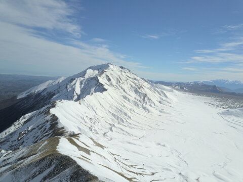 Aerial view of Campo Imperatore mountain range covered in snow under a clear blue sky in L'Aquila, Abruzzo, Italy.