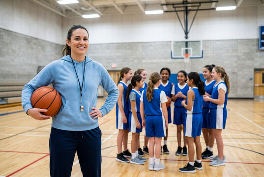 Smiling female basketball coach holding a ball in a school gymnasium