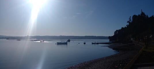 Sunlight over calm bay with boats, Chiloé, Patagonia, Chile © Alex