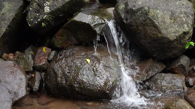 Close up shot of crystal clear river water flowing smoothly over natural stones in a peaceful stream.