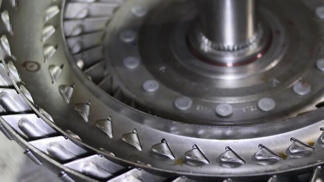 Close up detailed view of the curved metallic fins and blades inside an automotive automatic transmission torque converter component.