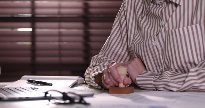 Woman stamping document at desk indoors, closeup