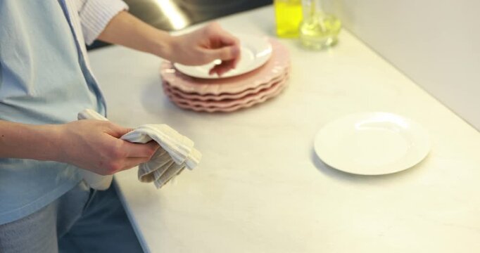 Housework. Teenage boy wiping plates with towel at countertop in kitchen, closeup