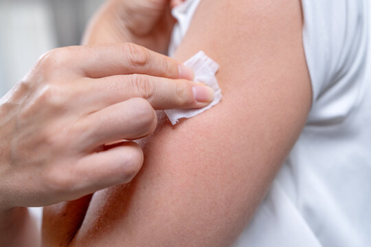 Detailed close view of a hand removing the backing while placing a round adhesive health sensor on a bare arm indoors or an alcohol wipe for disinfection