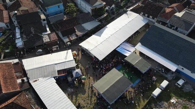 Aerial footage of a crowd of residents watching a traditional dance, amidst the density of an urban village, Yogyakarta, Indonesia.