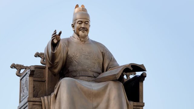 A close-up of the bronze statue of King Sejong the Great seated on his throne holding a scroll in Gwanghwamun Square Seoul.