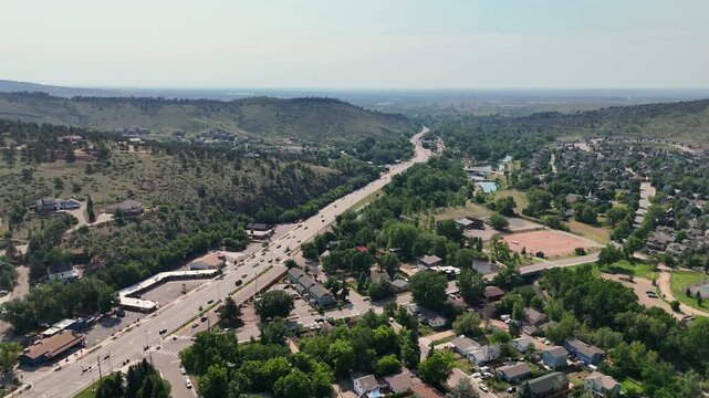 Aerial view of Hooter Lookout area with a highway winding through the landscape, surrounding trees, and residential houses in Lyons, Colorado, United States.
