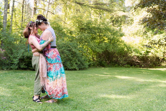 Lesbian couple wearing ren faire fairy outfit hold each other in a clearing