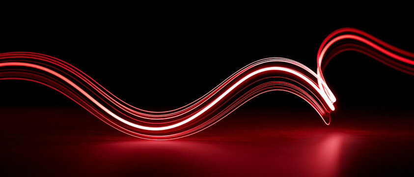 Abstract glowing red light wave on a dark background. The light trails create a dynamic and futuristic visual effect, evoking energy and motion