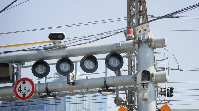 A close-up of railway crossing overhead signal equipment and warning lights mounted on poles in an urban Seoul street.