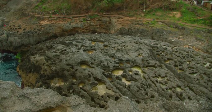 Rocky tide pools carved into limestone shore at Angels Billabong beach in Nusa Penida Island