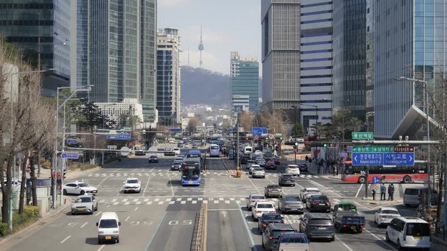 A wide view of a busy downtown Seoul intersection with heavy traffic and modern commercial buildings in all directions.