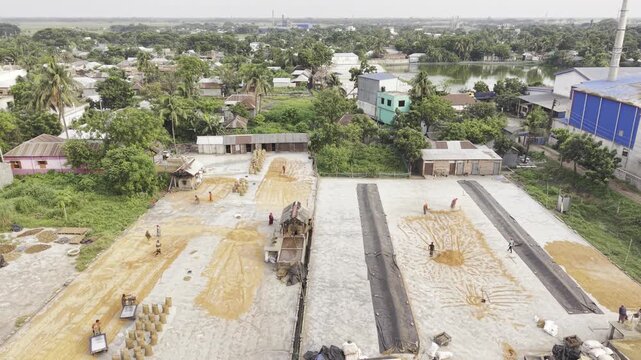 Descending drone footage approaching the Khajanagar rice processing factory, highlighting industrial buildings, warehouses, and production facilities.