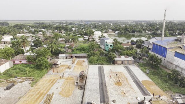 Reverse aerial flight showcasing the complete layout of the Khajanagar rice processing complex and surrounding infrastructure.