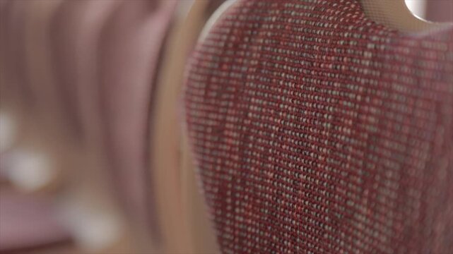Panning shot of chairs arranged in a row. The chairs are burgundy and beige, formal, and feature patterns such as dots.