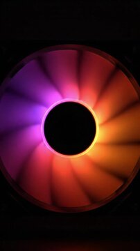 Rotating computer cooling fan with colorful rainbow LED lighting against a black background