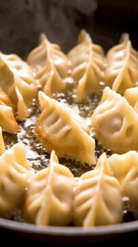 Sizzling gyoza dumplings pan frying in hot oil with steam rising in a vertical close up shot