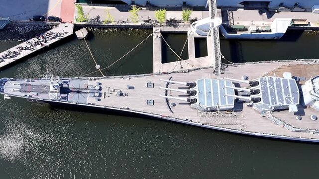 Aerial view of the historic battleship USS Wisconsin BB-64 docked at the waterfront with its massive gun turrets and deck visible from above in Norfolk, Virginia, United States.