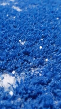 Vertical top down macro shot of blue synthetic turf with white sand for sports texture concept