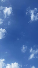 Fototapeta premium Deep blue sky background with soft white cumulus clouds vertically