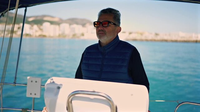 Mature man steering sailboat on the ocean