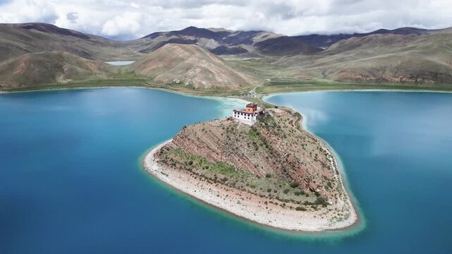 Drone view of Ritog temple in Yamdrok Lake (Yamzho Yumco or Yanghu), plateau lake in Lhasa in Shannan City, China, beautiful blue water and white clouds blue sky in autumn day, 4k real time footage.