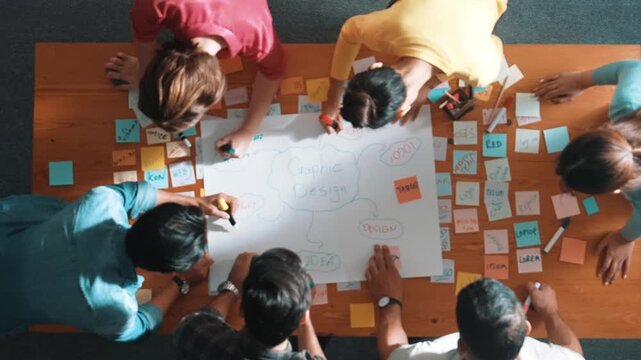 Top view of project manager writing and sticking stick notes. Aerial view of professional business people working together planning strategy while drafting mind mapping at meeting room. Symposium.
