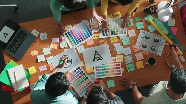 Top down view of smart designer explain and brainstorming idea for logo design and writing concept. Aerial view of business people discuss and talking while using sticky notes sharing idea. Symposium.