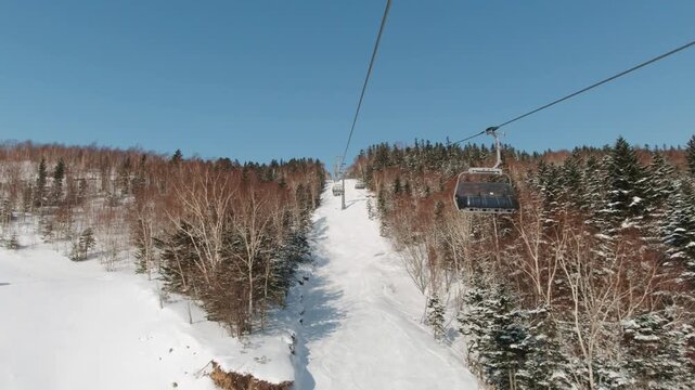 Riding on ski lift above the slopes in the morning. POV shot.