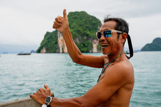 Thai boatman smiling, giving thumbs up, enjoying ocean travel