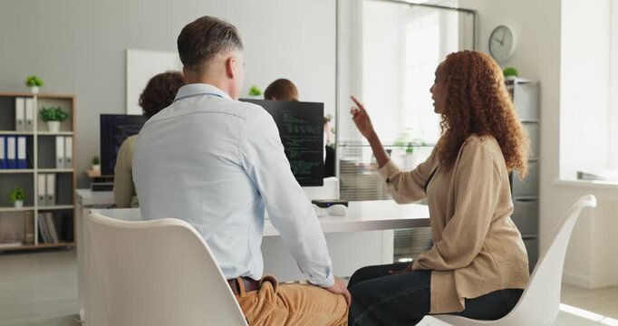 Developers programmers team coding office collaboration. Coworkers collaborate at screens, reviewing software and planning tasks in a bright office. Clear concept of teamwork meeting discussion.