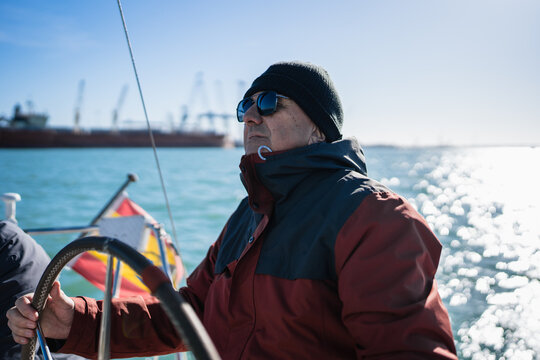Man driving sailboat steering wheel enjoying ocean voyage
