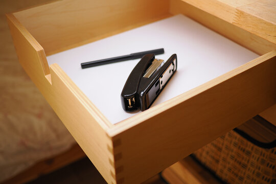 Office supplies rest in an open drawer on a workspace