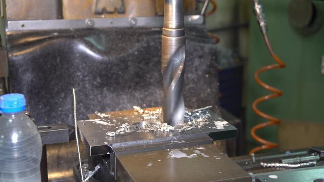 Close-up video of a heavy milling machine drilling a big size hole in a metal workpiece.