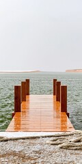 Fototapeta premium A wet wooden dock extending into a calm harbor with a surreal folding water surface on the horizon for climate change and storm surge concepts
