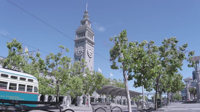 View Of 19th Century Ferry Building Clock Tower Near Vintage Streetcar Passing Benches
