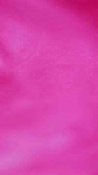 Vertical video. Sparkling liquid. Marble texture. Defocused pink color paint in water shiny pigment flowing on abstract art blurred background.