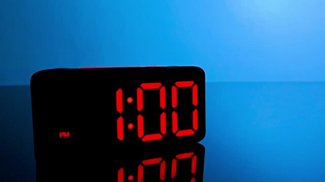 Digital alarm clock changing from 12:59 pm to 1:00 pm with red led display