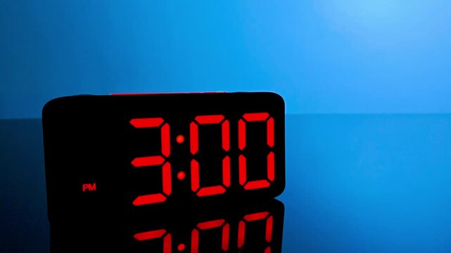 Digital alarm clock changing from 2:59 pm to 3:00 pm with red led display
